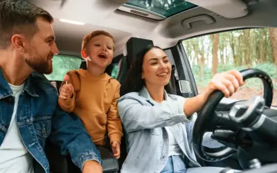 Rodzina w samochodzie, ciesząca się wspólną podróżą. Nawet przy rosnących kosztach utrzymania samochodu, takie chwile są bezcenne.