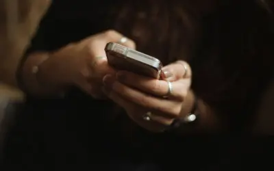 Dłonie z pierścionkami trzymają telefon, być może przeglądając oferty na OLX i myśląc o płatnościach PayPo.