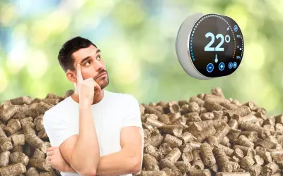 Un homme réfléchit devant un tas de granulés de bois, un thermostat connecté pour poêle à granulé affiche 22°.