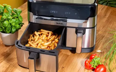 Frytki z frytkownicy beztłuszczowej Tefal, idealne do rankingu air fryer. Obok bazylia i pomidory.
