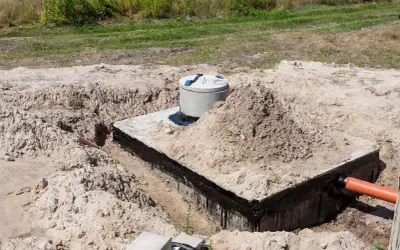 Budowa szamba: betonowa konstrukcja z rurą wylotową, przygotowana do uszczelnienia.
