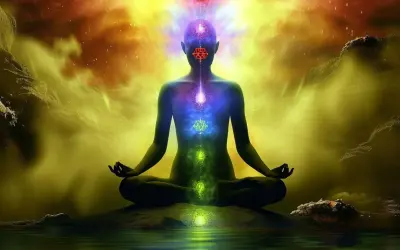 Sylwetka w pozie medytacyjnej, z rozświetlonymi czakrami i energią kundalini unoszącą się ku górze.