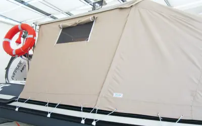 Tenda campeggio nautico su gommone, con oblò e salvagente arancione.