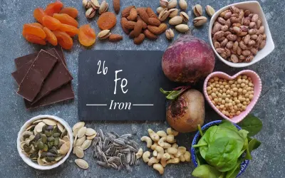 Una tavola ricca di alimenti ricchi di ferro: cioccolato fondente, albicocche, mandorle, pistacchi, barbabietole, fagioli, soia, spinaci, semi di zucca e girasole.
