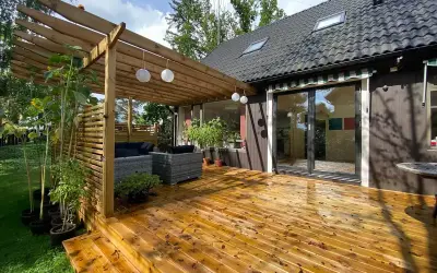 Träaltan med pergola och loungegrupp ger härlig altan inspiration. Solrosor och grönska ramar in.