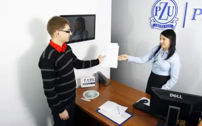 Mężczyzna podaje dokumenty kobiecie przy biurku w biurze PZU.