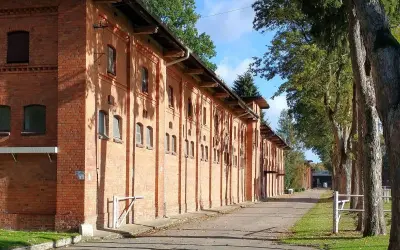 Długa, ceglana stajnia w Starogardzie Gdańskim, gdzie kiedyś stacjonował stado ogierów. Aleja drzew prowadzi do budynków.