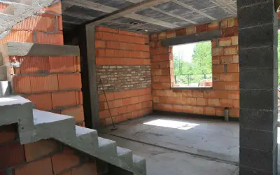 Budynek gospodarczy w trakcie adaptacji na cele mieszkalne. Widoczne schody betonowe, ściany z pustaków ceramicznych i betonowych, otwór okienny.