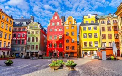 Kolorowe kamienice na placu w Gamla Stan, Sztokholm, pod błękitnym niebem z chmurami.