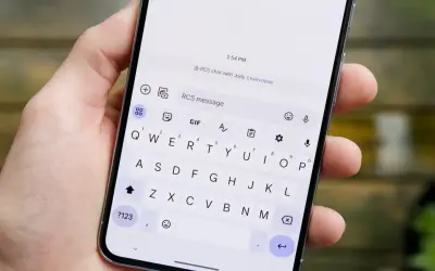 Dłoń trzyma smartfon z otwartą klawiaturą. Na ekranie widać informację "RCS chat with Judy", co wyjaśnia, rcs co to jest.