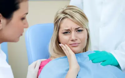 Kobieta cierpi na ból zęba po zatruciu. Dentysta i asystentka próbują jej pomóc.