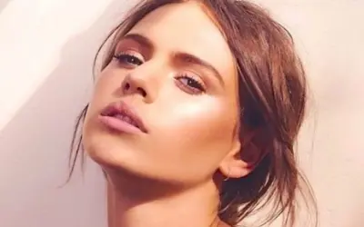 Visage d'une jeune femme au maquillage lumineux, elle pose avec un regard intense. Peut on bronzer avec du maquillage ? Sa peau semble éclatante.