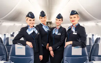 Uśmiechnięte stewardessy Enter Air w granatowych mundurach, gotowe do obsługi lotów czarterowych.