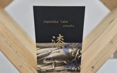 Okładka książki "Japońska laka urushi" z motywem złotej ryby koi i japońskiego znaku.