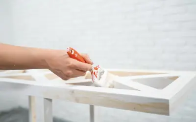 Mano che dipinge un mobile in legno con vernice a gesso, per un effetto shabby chic.