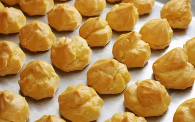 Une fournée de choux à la crème dorés, prêts pour la cuisson. Ils attendent patiemment d'être transformés en délices.