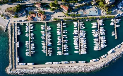 Widok z lotu ptaka na port w Chorwacji, pełen białych jachtów i łodzi zacumowanych w turkusowej wodzie.