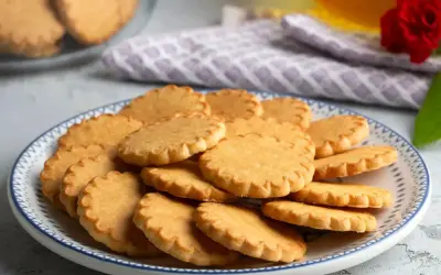 Stos tradycyjnych ciasteczek maślanych na talerzu z niebieskim wzorem. Idealne do popołudniowej herbaty.