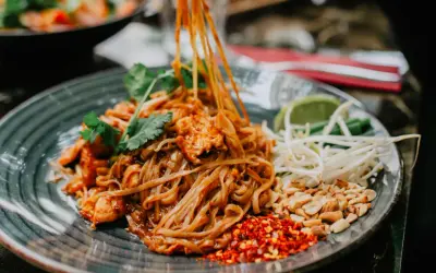 Pyszny pad thai z kurczakiem, orzeszkami, kiełkami i limonką. Tak jemy pad thai, dodając przyprawy do smaku.