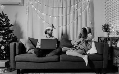 Wśród nocnej ciszy chwyty ukulele i śmiech przy laptopie. Para w czapkach Mikołaja cieszy się świąteczną atmosferą.