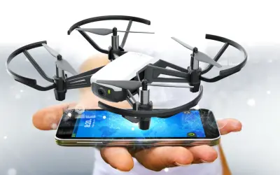 Kleine Drohne schwebt über einem Smartphone, das die tello app anzeigt.