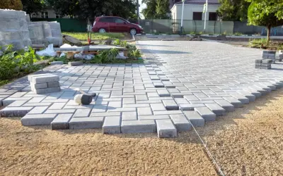 Układanie kostki brukowej na podjazd. Widać młotek i stosy kostki.