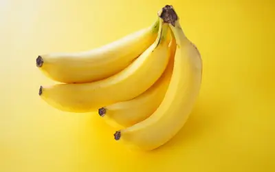 Pęczek żółtych bananów na jasnym, żółtym tle.