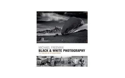 Michael Freeman's "Black & White Photography" showcases the timeless art of monochrome. This cover features a dramatic desert landscape and smaller images of buses, giraffes, and people.