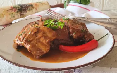 Pyszne, domowe babcine żeberka w sosie własnym, podane z ostrą papryczką i świeżymi ziołami.