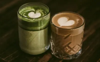 Zielone matcha latte i kawowe latte z serduszkami na piance. Dylemat: kawa czy herbata?