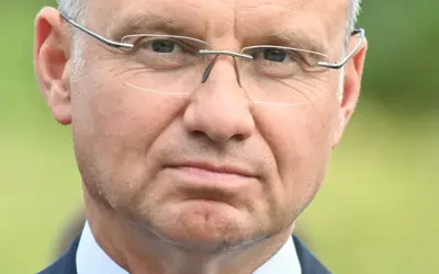 Zbliżenie na twarz mężczyzny w okularach. W jego oczach widać refleksję, jakby zastanawiał się nad przyszłością, może nad swoją emeryturą prezydencką.
