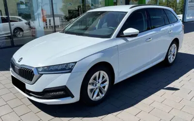 Białe, duże auto rodzinne typu kombi stoi przed salonem samochodowym. Idealne na wakacyjne wyjazdy i codzienne dojazdy.