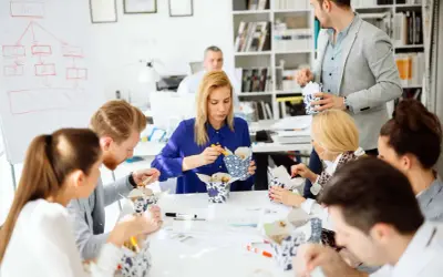 Une équipe profite d'un pause repas, partageant des boîtes de nouilles. Le code du travail permet ces moments de convivialité.
