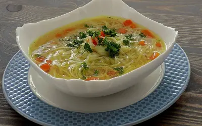 Aromatyczna zupa na rosole z makaronem nitki i marchewką, udekorowana natką pietruszki. Idealna na chłodne dni.