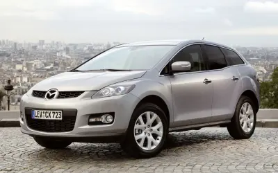 Srebrna Mazda CX-7 2.3 Turbo na tle panoramy miasta.