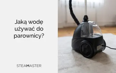 Jaka woda do parownicy? Czarna parownica Steam Master z przezroczystym zbiornikiem na wodę, stojąca na jasnym dywanie.