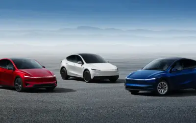 Trzy samochody Tesla: czerwony, biały i niebieski, stoją na pustkowiu.