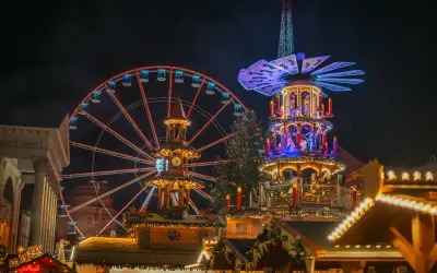 Ein beleuchtetes Riesenrad in Karlsruhe strahlt neben einer Weihnachts-Pyramide.