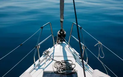 Prua di una barca a vela su un mare blu calmo. La prevalenza di una pompa è un concetto che non si applica a questa immagine.