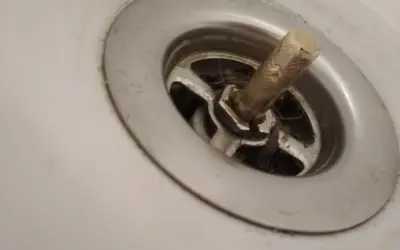 W umywalce widać wciśnięty korek, wokół którego zebrały się włosy i brud.