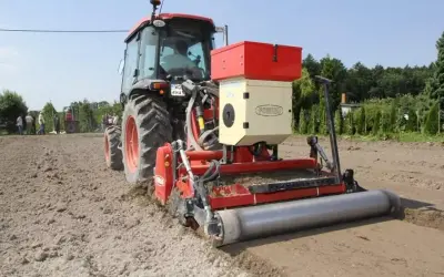 Ciągnik z siewnikiem Forigo basamid przygotowuje pole do siewu. Maszyna równa i wałuje ziemię.