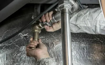 Ręce hydraulika montują baterię podtynkową. Sprawdź montaż baterii podtynkowej cena.