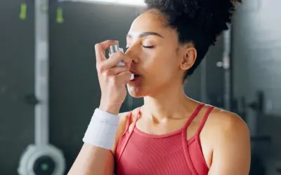 Frau mit Inhalator im Fitnessstudio. Sport bei COPD kann mit richtiger Vorbereitung möglich sein.