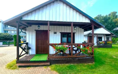 Urocze domki letniskowe Amber House z werandą i kwitnącymi pelargoniami. Idealne miejsce na wypoczynek.