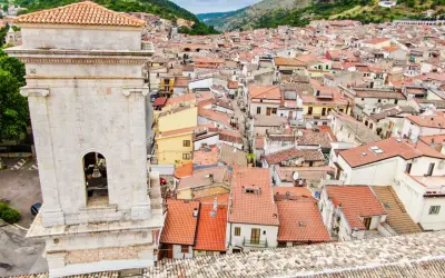 Vista dall'alto di San Marco in Lamis: un campanile in pietra domina un dedalo di tetti rossi e case arroccate tra le colline. Cosa vedere in questo borgo?