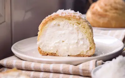 Bignè ripieno di crema soffice, cosparso di zucchero a velo che ricorda un fiocco di neve.