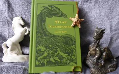 Zielona okładka "Atlasu Tolkienowskiego" z wizerunkiem smoka, obok figurka konia i smoka, oraz pierścień. To wszystko, co napisał Tolkien, w jednym miejscu.