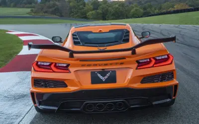 Pomarańczowy Corvette C9 z dużym spojlerem na torze wyścigowym.