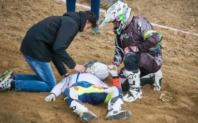 Po wypadku Tomasza Golloba, ratownicy udzielają pomocy leżącemu na piasku zawodnikowi w stroju motocyklowym.