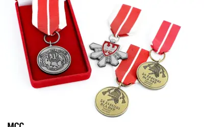 Odznaczenia strażackie w pudełku i luźno leżące na białym tle. Widać godło Polski i symbole strażackie.